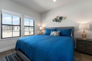 1 Schlafzimmer mit einem blauen Bett und 2 Fenstern in der Unterkunft Eagle's Hangout - Hot Tub Close to 290 Wine Trail in Fredericksburg