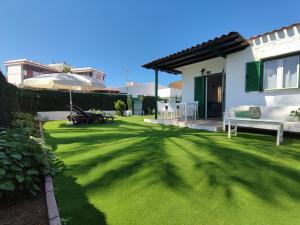 a yard with green grass and a house at Bungalow next Yumbo Center in Playa del Ingles