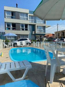 une piscine avec des chaises longues et un parasol dans l'établissement Residencial Provincia Di Trento Beira Mar, à Torres