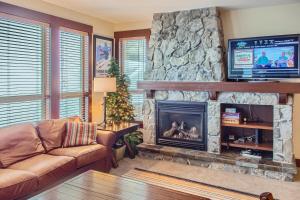 a living room with a stone fireplace with a flat screen tv at Stonegate Resort Unit A202 in Big White