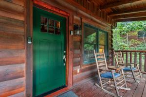 a green door on a porch with two chairs at Elegant & Cozy Cabin Near Pigeon Forge in Sevierville