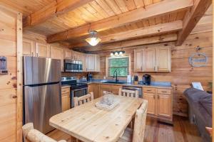 a kitchen with a table and a stainless steel refrigerator at Elegant & Cozy Cabin Near Pigeon Forge in Sevierville +26 photos