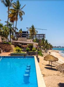 una piscina junto a una playa con palmeras en Oceanfront Bucerias Casita Oasis Condo - Large Studio, en Bucerías