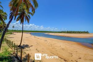 a beach with two palm trees and the ocean at Ponta de Inhambupe Residences in Baixio