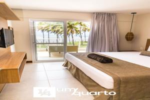 a hotel room with a bed and a sliding glass door at Ponta de Inhambupe Residences in Esplanada