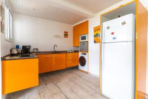 a kitchen with orange cabinets and a white refrigerator at Domaine Madinina in Le Morne-Vert