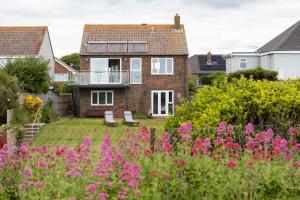une maison avec un jardin orné de fleurs roses dans l'établissement Braganza The Butler Collection, à Middleton-on-Sea