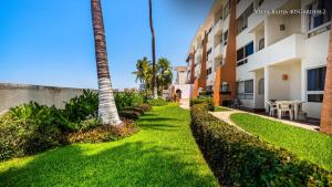 a lawn in front of a building with a palm tree at Oceanfront-Ocean View in Bucerias Casita Oasis Condo - Large Studio in Bucerías