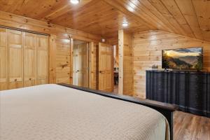 a bedroom with a bed in a room with wooden walls at The Cabin That Plays Hard & Rests Easy Black Bear Lodge in Pigeon Forge