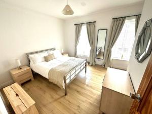 a bedroom with a bed and two windows and a mirror at 55 Malin Road in Moville