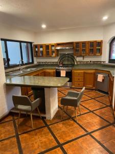 a kitchen with a large counter and two chairs in it at Casa entre árboles in Momoxpan