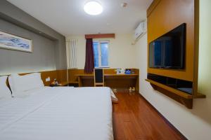 a hotel room with a bed and a flat screen tv at 7Days Premium Luoyang Jiudu Road Chinese Flowers Garden in Luoyang