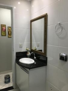 a bathroom with a sink and a mirror at Apto com Ar Cond e Wifi Super Confortável in Guarapari
