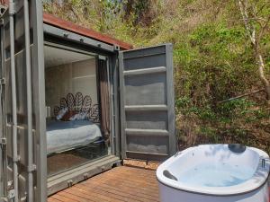a room with a bed and a bath tub on a deck at Container Beija-Flor com SPA e Cachoeira in Brotas