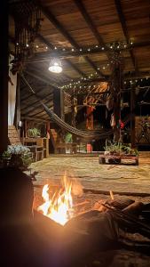 a fire in the middle of a room with a hammock at Ave de Montaña Cabañas in El Zaino