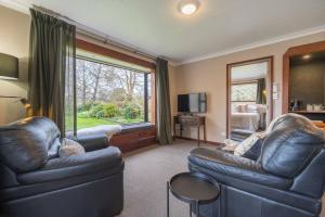 a living room with leather furniture and a large window at Te Anau Cottage in Te Anau