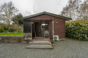 a small brown shed with a porch and a door at Te Anau Cottage in Te Anau