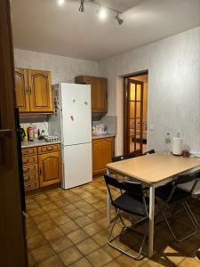 Una cocina con una mesa y un refrigerador blanco. en Noclegi77 - Auberge77, en Villiers-sous-Grez