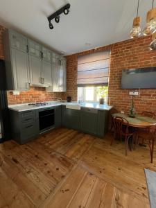 a kitchen with green cabinets and a table and a brick wall at Apartamenty Łuczkowskiego z widokiem na Stary Rynek i Studnię 3 in Chełm