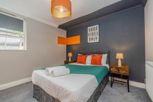 une chambre avec un grand lit avec des oreillers orange dans l'établissement Super Central 1 Bedroom Flat With Balcony Next To Brighton Beach, à Brighton et Hove
