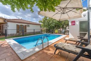 a swimming pool with an umbrella next to a house at Casa rural VISTABLANCA en una sola planta con bonitas vistas y piscina - Junto a la capital y la Alhambra in Cenes de la Vega