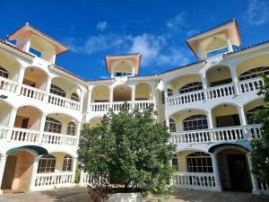 ein großes weißes Gebäude mit einem Baum im Hof in der Unterkunft Costambar in San Felipe de Puerto Plata