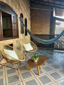 Dos sillas, una mesa y una hamaca en un patio. en MariaBonita, en Arraial do Cabo