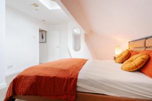 リバプールにあるLiverpool Luxe Retreat 3 Bedroom House Next to Everton Stadiumのオレンジ色の枕が付いた大きなベッドのある寝室