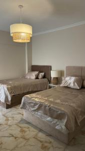 a bedroom with two beds and a chandelier at Atheers apartment in Madinaty +10 photos