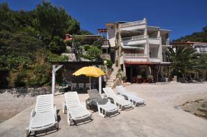 a group of lounge chairs and an umbrella on the beach at Apartments Villa Smokvina in Bogomolje