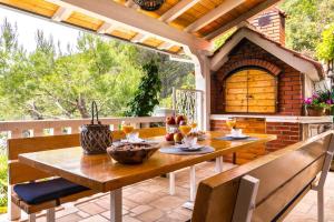 a wooden table and chairs on a patio at Apartments Villa Smokvina in Bogomolje