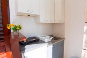 eine kleine Küche mit weißen Schränken und einer Spüle in der Unterkunft Apartments and Rooms Hope in Brela + 25 Fotos