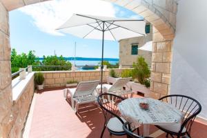 eine Terrasse mit Tisch und Stühlen und einem Sonnenschirm in der Unterkunft Apartments and Rooms Hope in Brela