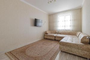 a living room with a couch and a tv at Apartments 7 Я-14 in Astana