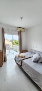 a bedroom with a bed and a large window at Linda casa 3 Praia Ponta do Papagaio 190mt mar in Palhoça