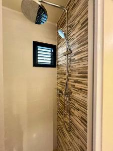 La salle de bains est pourvue d'une douche et d'un mur en pierre. dans l'établissement L'escale bleue, à La Trinité