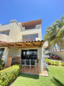 une maison dotée d'une terrasse couverte avec des chaises et une terrasse. dans l'établissement Villa 8 frente al mar, à Zihuatanejo