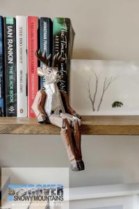 a wooden reindeer sitting on a shelf with books at Wintergreen 3 - Thredbo in Thredbo