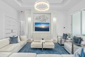 Una sala de estar con muebles blancos y una lámpara de araña. en Diamond Blue Beach Home, en Bonita Springs