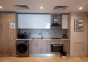 eine Küche mit weißen Schränken, einer Spüle und einem Geschirrspüler in der Unterkunft Warm 1BR with at Mangroovy, El-Gouna M1-7B in Hurghada