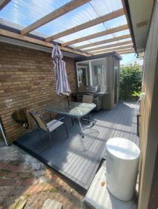un patio con una terraza de madera con pérgola en cosy studio in east Gippsland B, en Paynesville