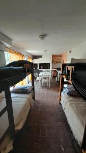 a room with three beds and a dining room with a table at Departamento Nini Villa Del Dique in Villa del Dique