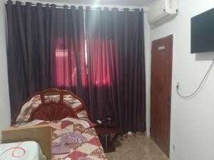 a bedroom with black curtains and a bed and a television at Pousada recanto do sabiá in Mangaratiba
