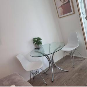 a glass table and four white chairs in a room at A comfortable and quiet 2bedroom house and a 1bedroom bungalow in Paynesville