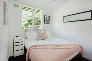 Un dormitorio blanco con una cama y una ventana. en Treetop Retreat Five Minute Stroll To The Beach, en Sídney