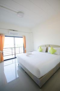 a white bedroom with a large bed and a window at Sunee Boutique Hotel in Uttaradit