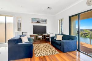 a living room with two blue chairs and a television at Lazy Lodge on Blanche - A Family Escape on the River in Hindmarsh Island