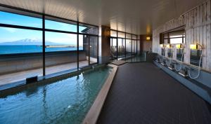a swimming pool in a building with a view of the ocean at REBUN Hotel SARYO in Kafuka