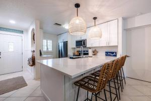 a kitchen with a large island with two bar stools at Catch the Breeze on Crystal Beach in Palm Harbor