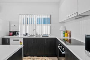 a white kitchen with a sink and a window at C-Views - Aldinga Beach - C21 SouthCoast Holidays in Aldinga Beach